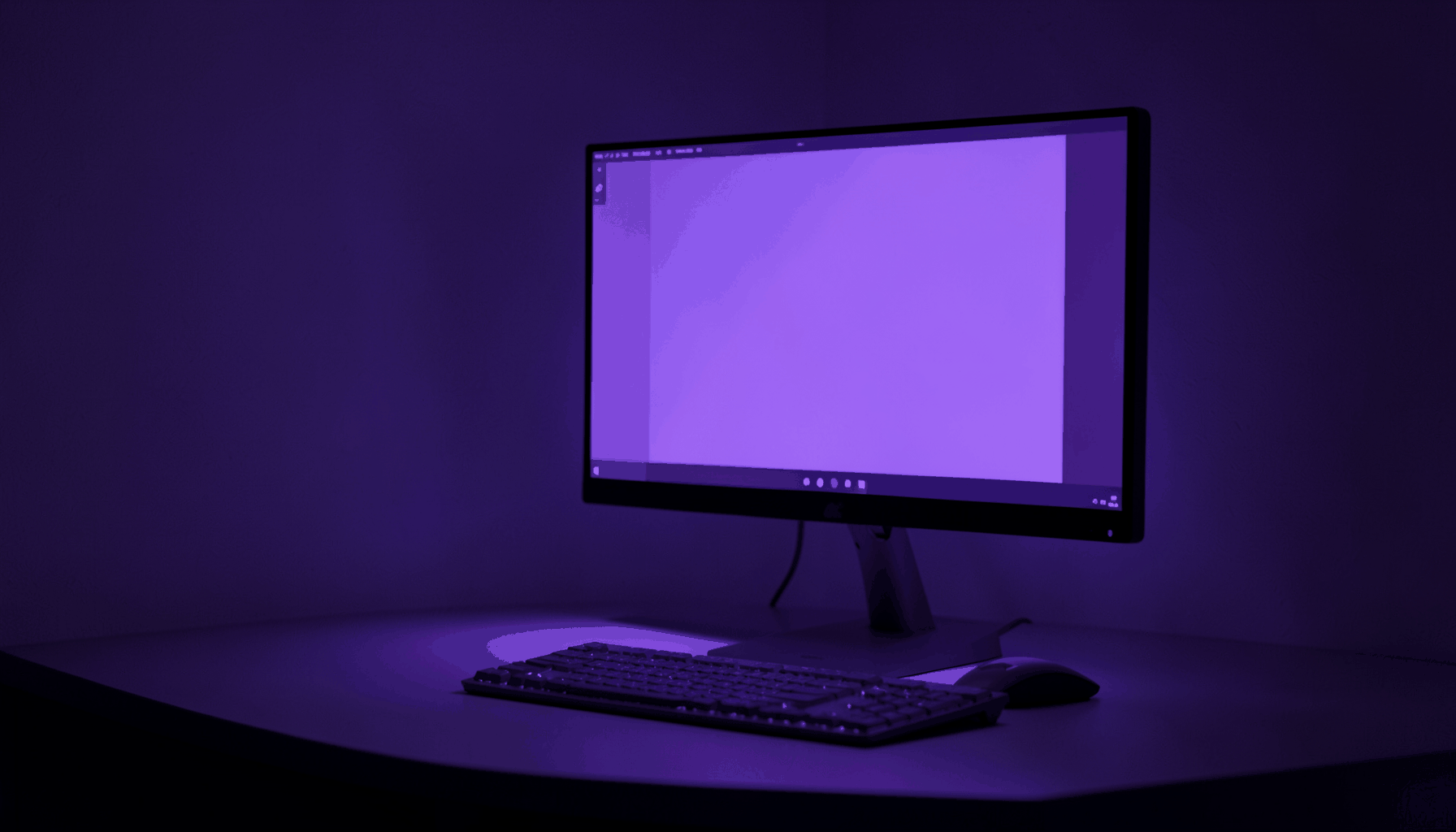 A dark violet and indigo duotone photograph of a sleek modern desktop workspace with a glowing monitor screen, casting soft ambient light across the desk surface